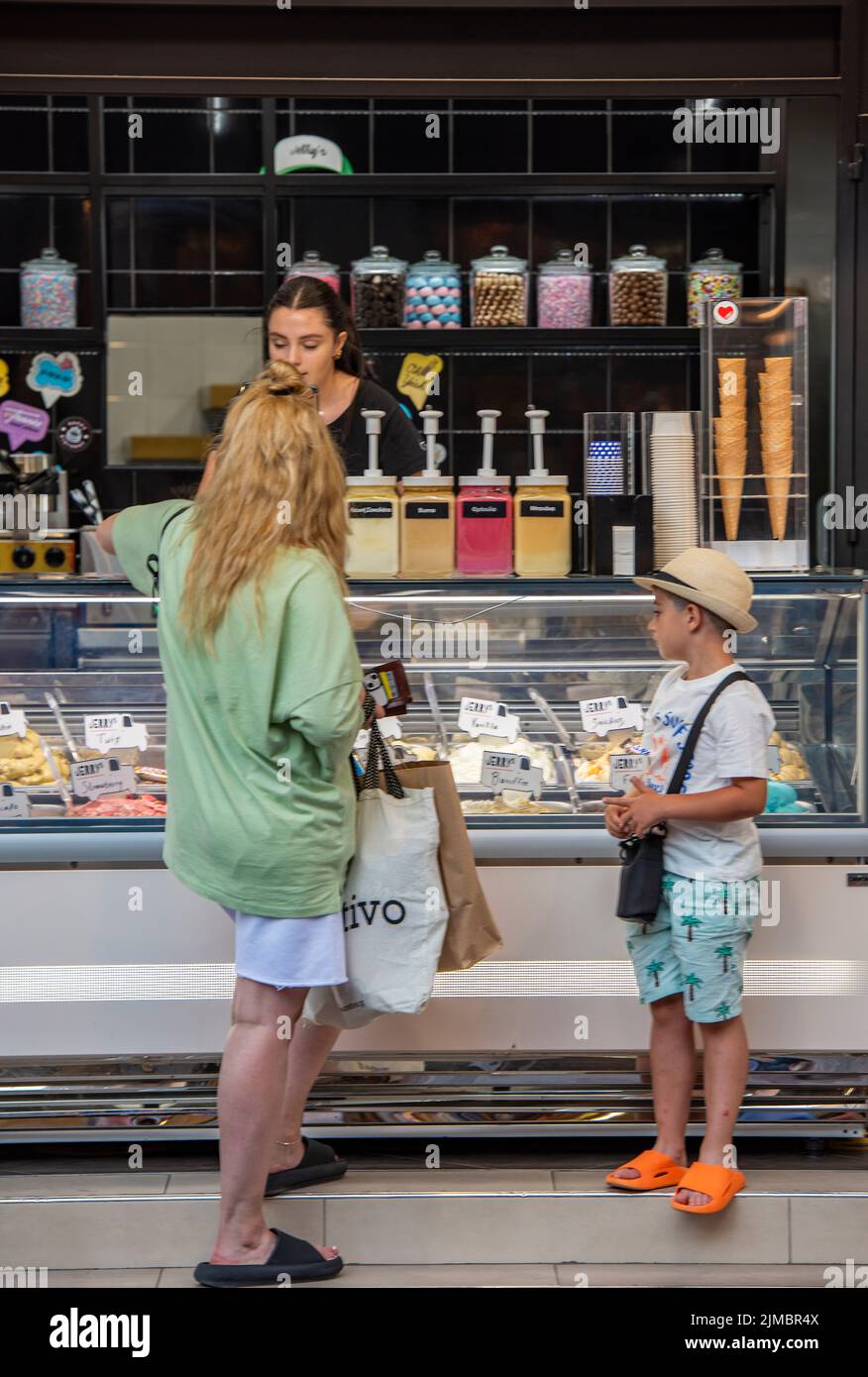 mother and child standing at an ice cream parlor or kiosk at the seaside buying ice creams to cool down during a hot summer heatwave Stock Photo