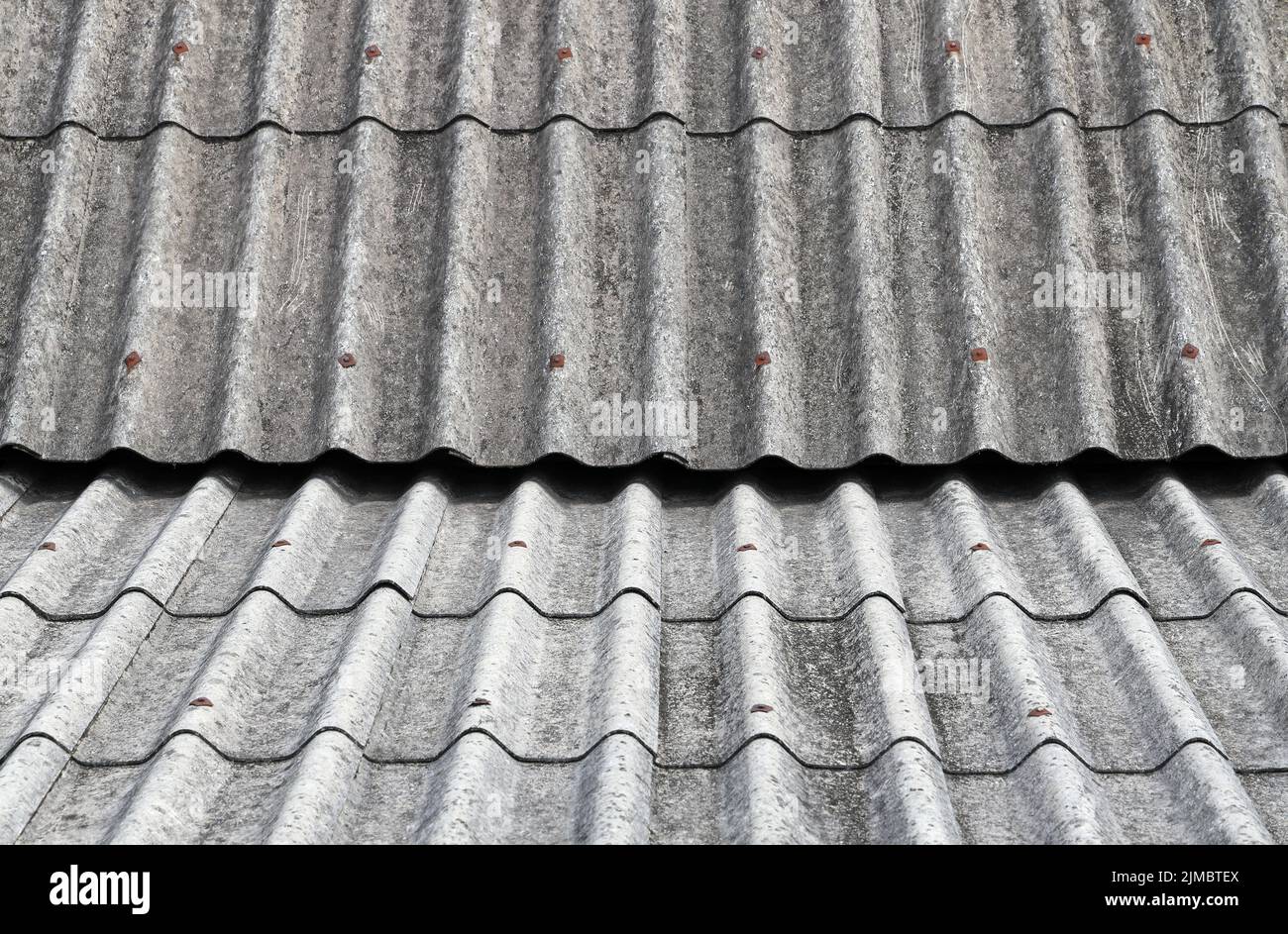 Old Asbestos cement roofing sheets, Asbestos roof, Corrugated Asbestos Cement Roof Sheet, corrugated panels, Gray slate texture, Gray wavy slate roof. Stock Photo