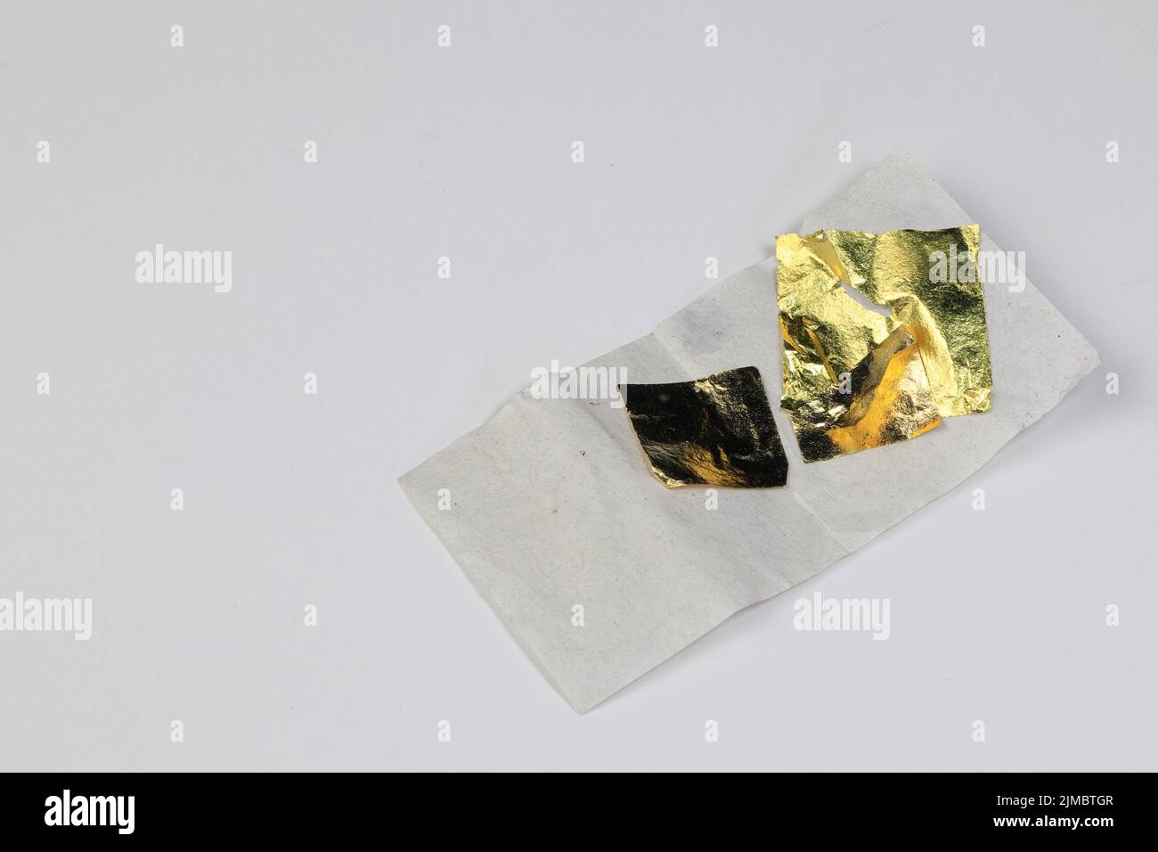 Gold foil leaf shiny on wrapping paper, piece of Gold leaf on paper isolated on white background