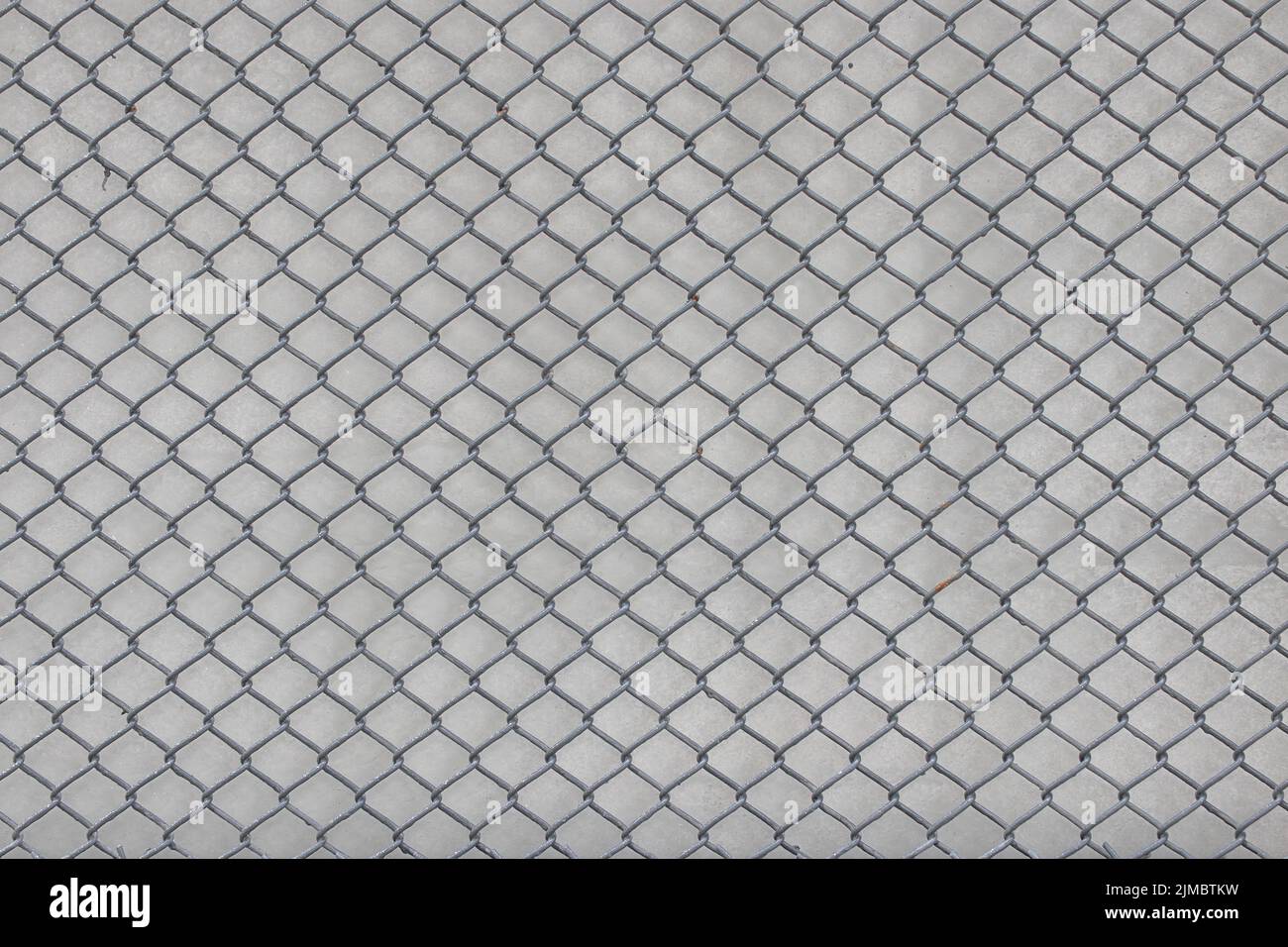 chain link fence wire mesh steel metal background with white concrete wall, secured property, Abstract background. Stock Photo