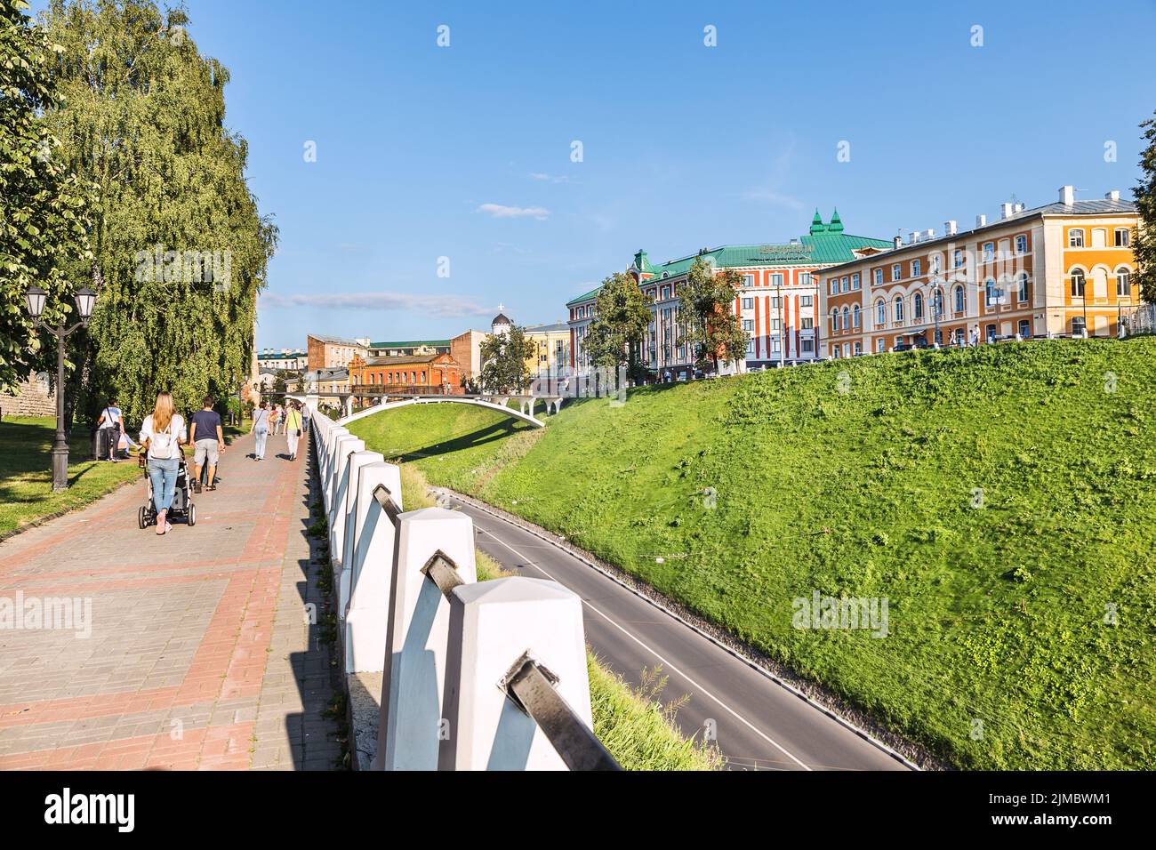 Pedestrian street with a white stone fence, with people walking. Stock Photo