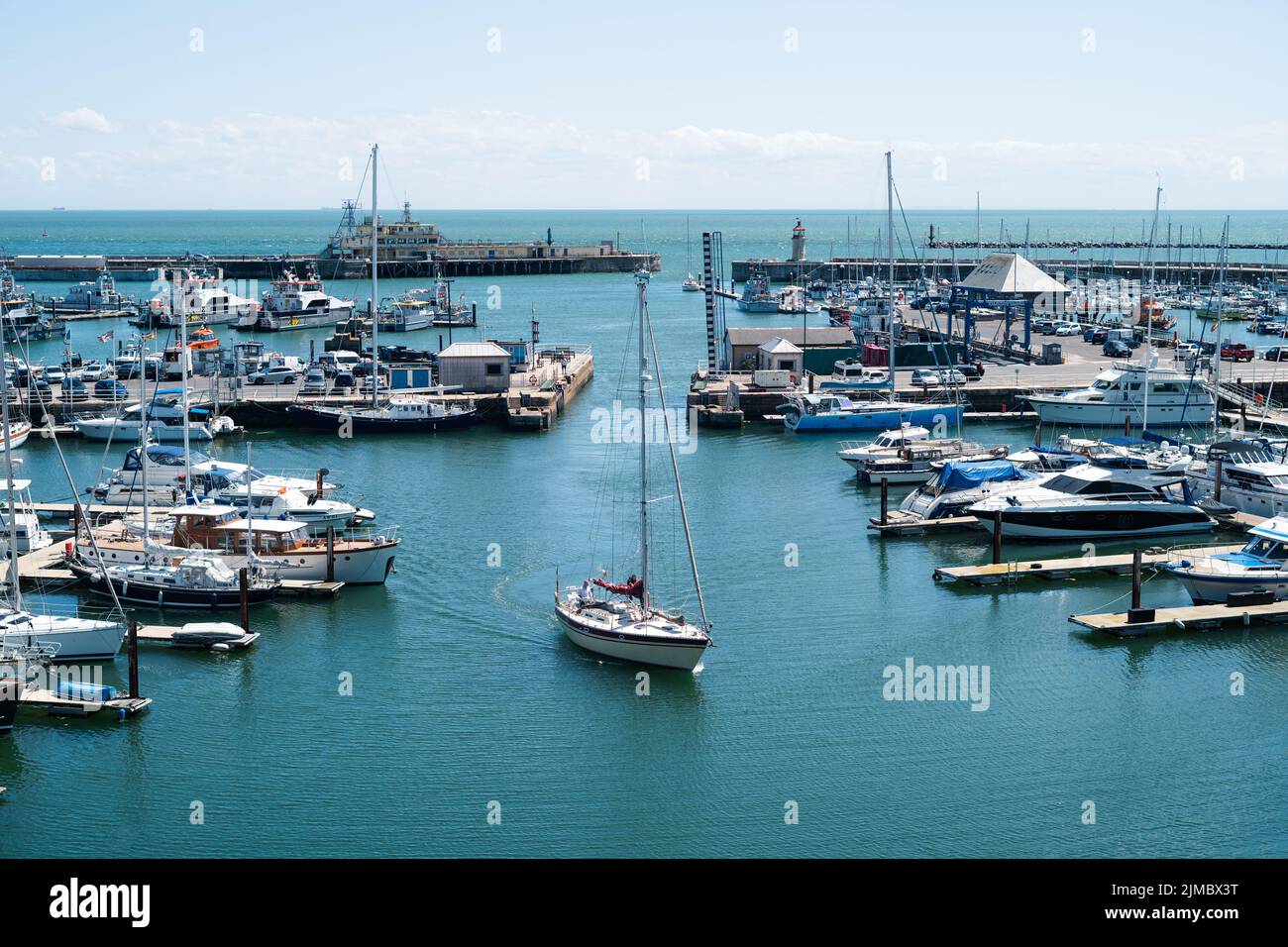 Ramsgate, UK - June 28 2022 A yacht with its sail down enters Ramsgate Royal Harbour inner basin. Stock Photo