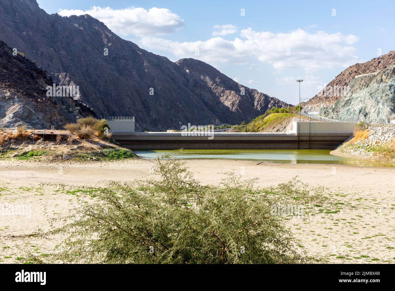 Wadi Shawka Dam, almost empty dam in Hajar Mountains, Ras al Khaimah, United Arab Emirates, with rocky mountains in the background and dry riverbed. Stock Photo