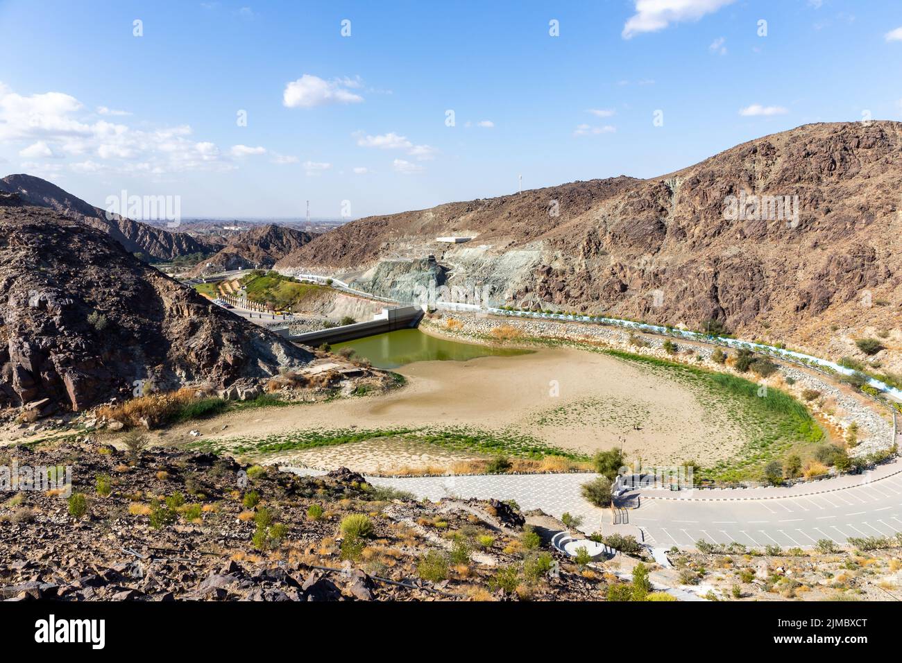 Wadi Shawka Dam, almost empty dam in Hajar Mountains, Ras al Khaimah, United Arab Emirates, with rocky mountains in the background and dry riverbed. Stock Photo