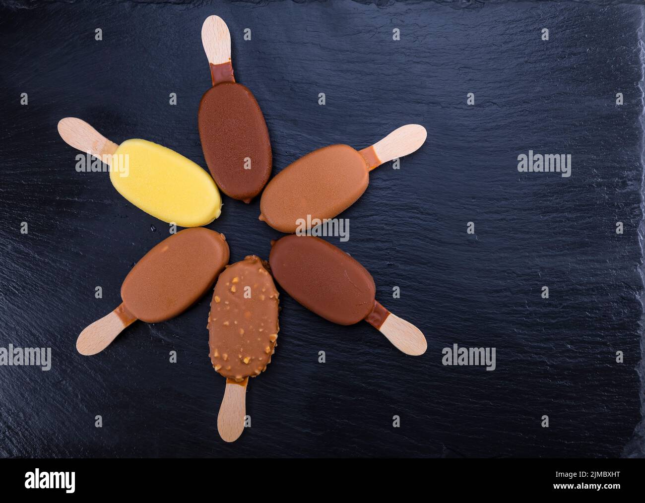 Ice cream on stick covered with chocolate on black slate Stock Photo