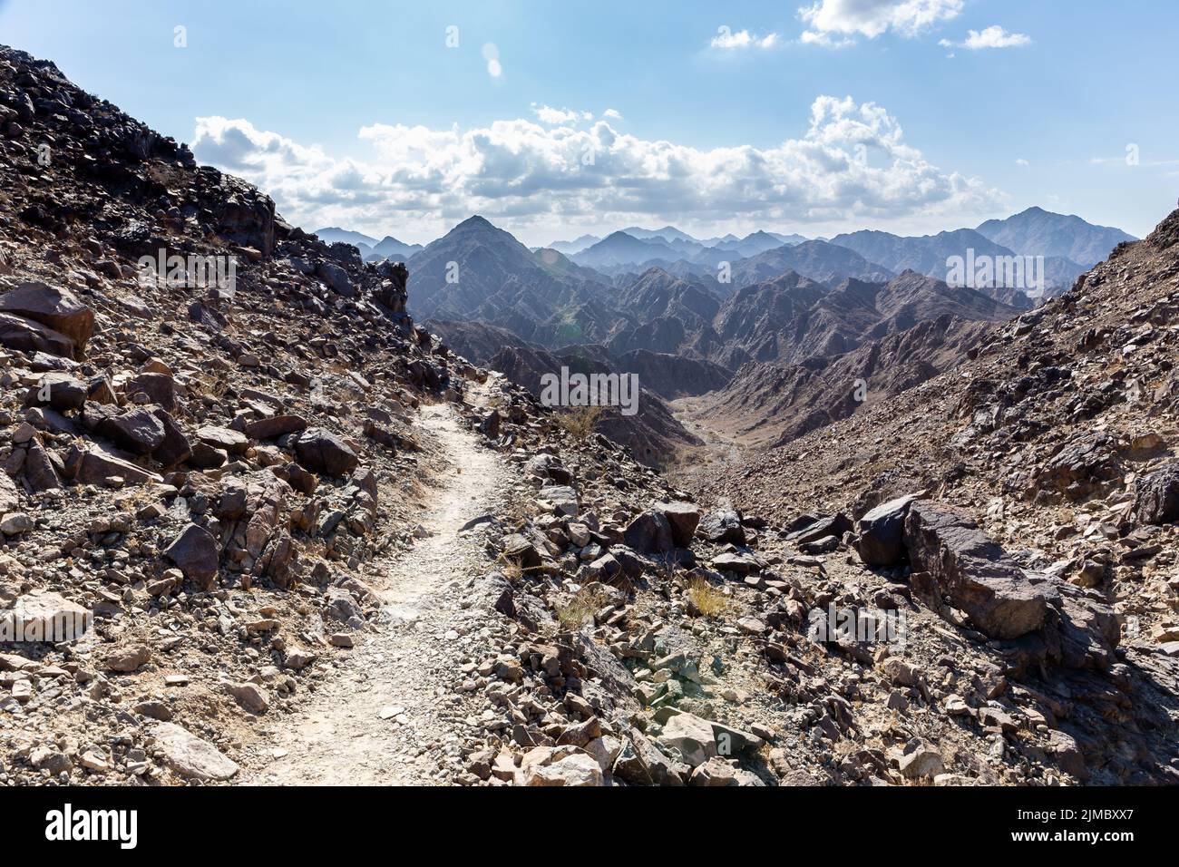 Wadi Shawka narrow hiking trail in rocky limestone Hajar Mountains, United Arab Emirates, with mountain ranges in the background. Stock Photo