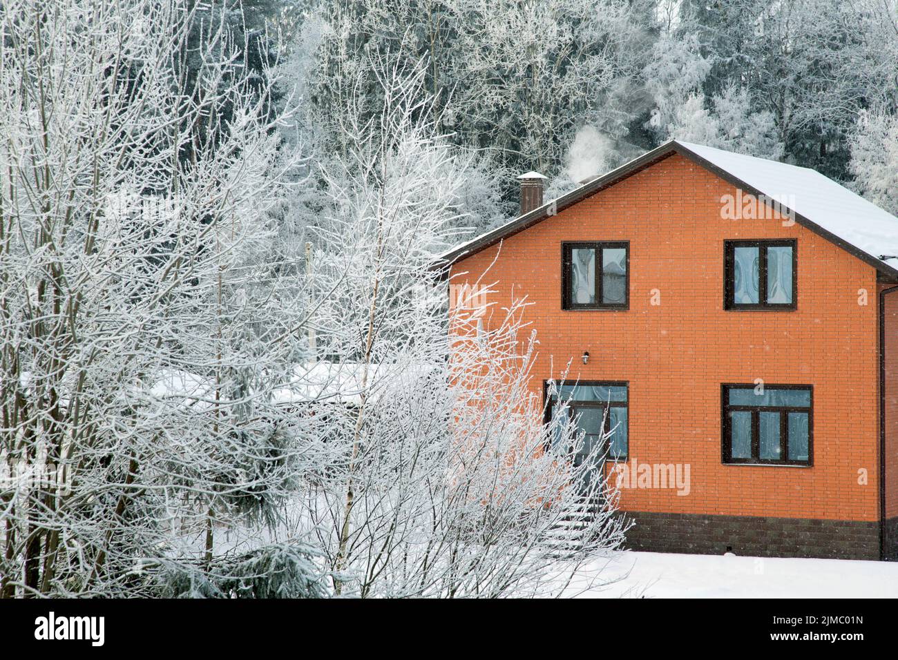Brick house on a frosty winter day among the trees Stock Photo