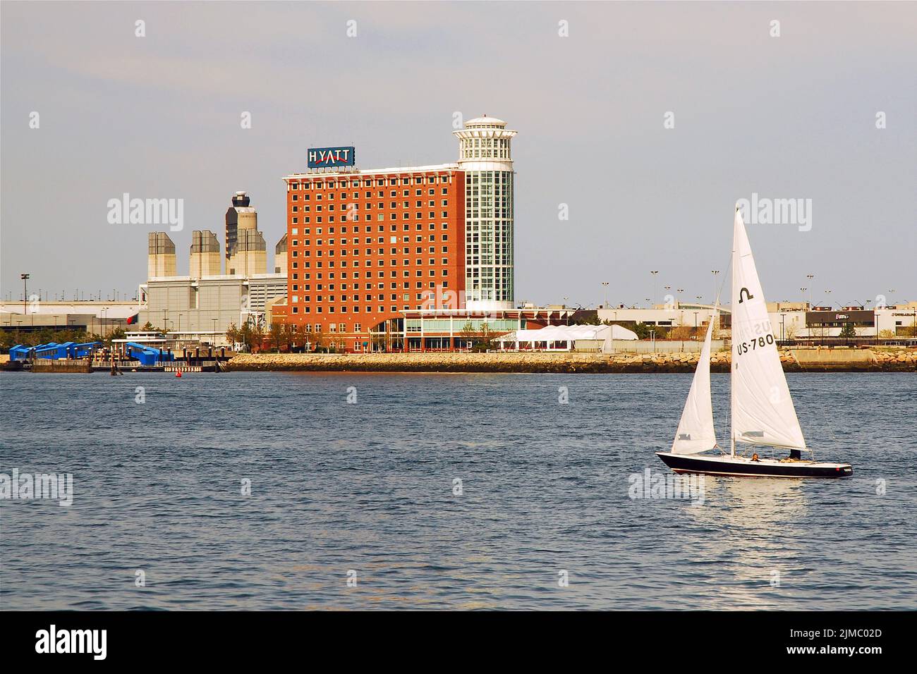 A sailboat cruises through Boston Harbor passing the hotels of Logan Airport on a sunny summer day Stock Photo