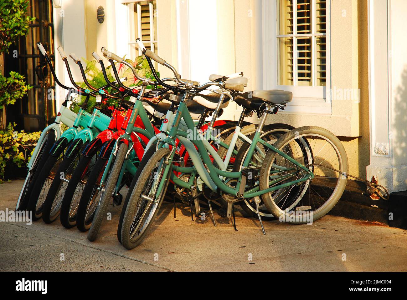 A row of rental bikes are chained to a bike rack at a store that rents them to tourists in Charleston South Carolina Stock Photo