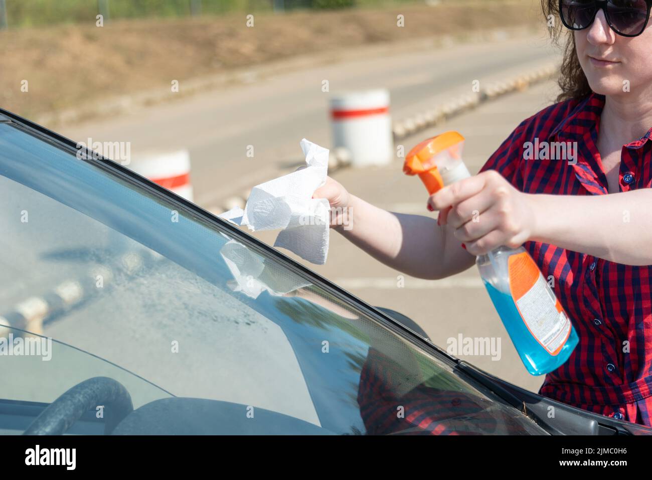 Wiping the windshield with spray and paper towels. Car maintenance