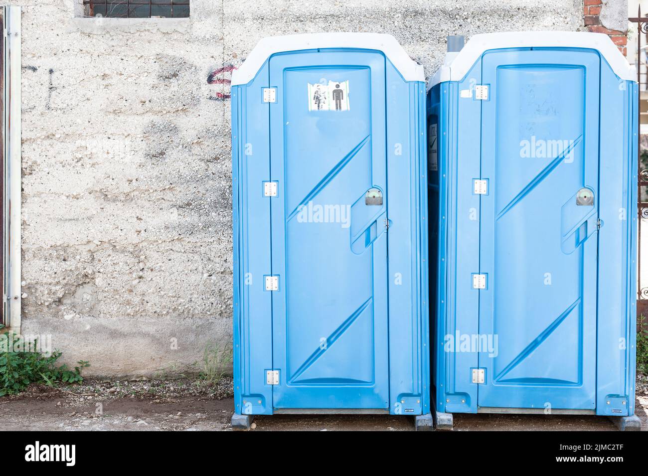 Two blue portable toilet cabins at construction site Stock Photo