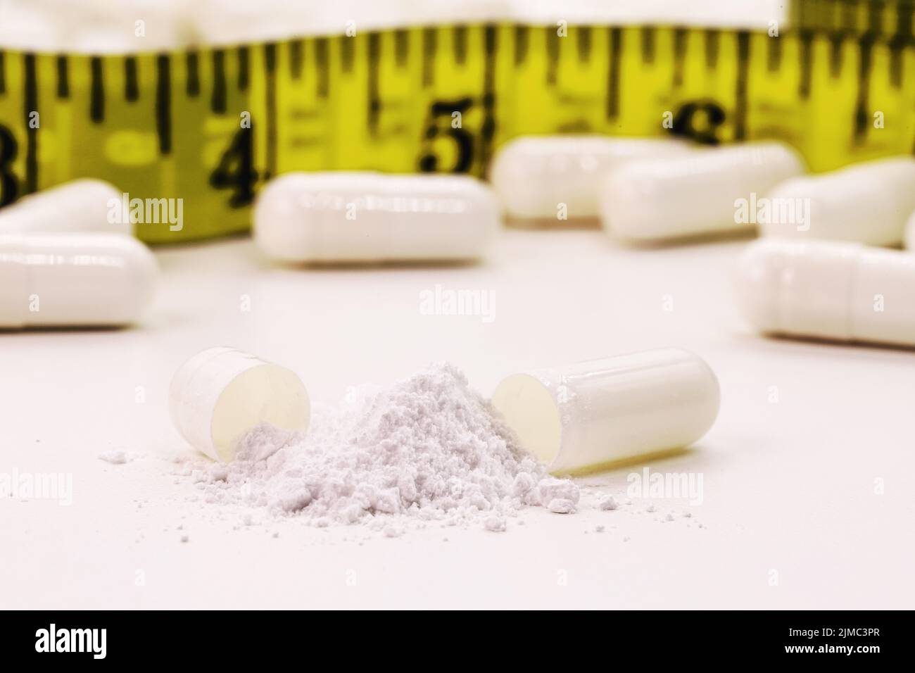 creatine pills, food supplement or energy vitamin for physical activity, with tape measure in the background Stock Photo