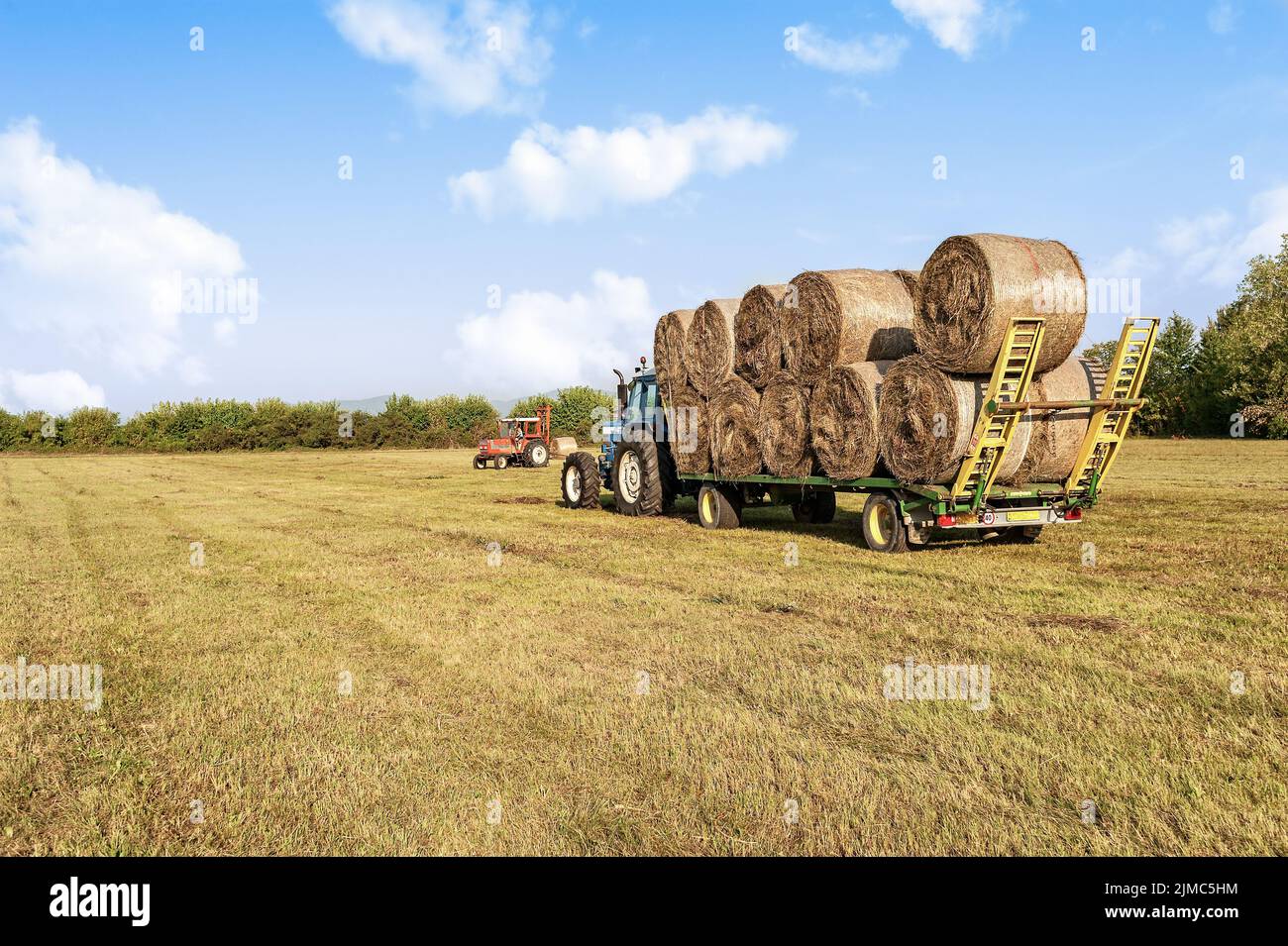 Agricultural scene. Tractor lifting hay bale on barrow Stock Photo Alamy