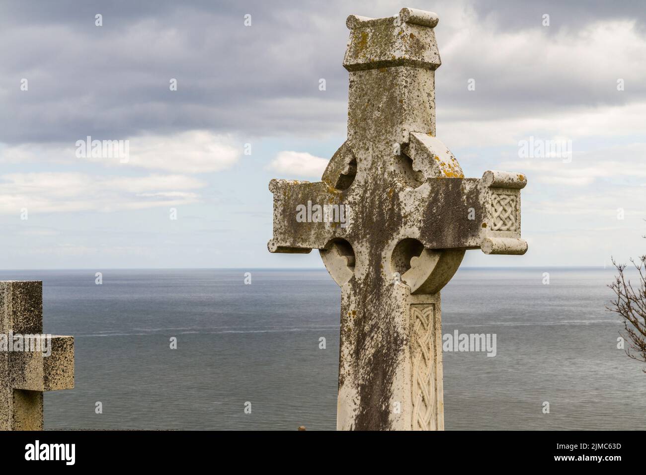Cross of grave with sea, sky with cloud behind Stock Photo