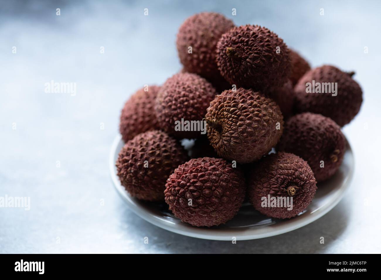 Fresh lychee fruits in a plate, close up, selective focus. Stock Photo