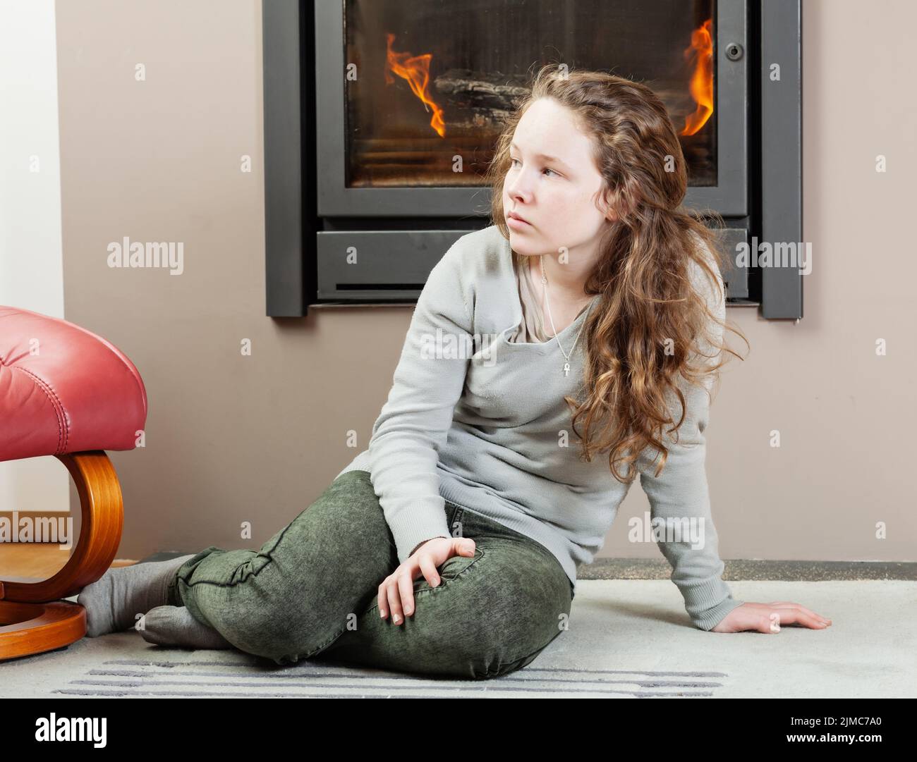 Thoughtful teenager girl sitting near fireplace Stock Photo Alamy