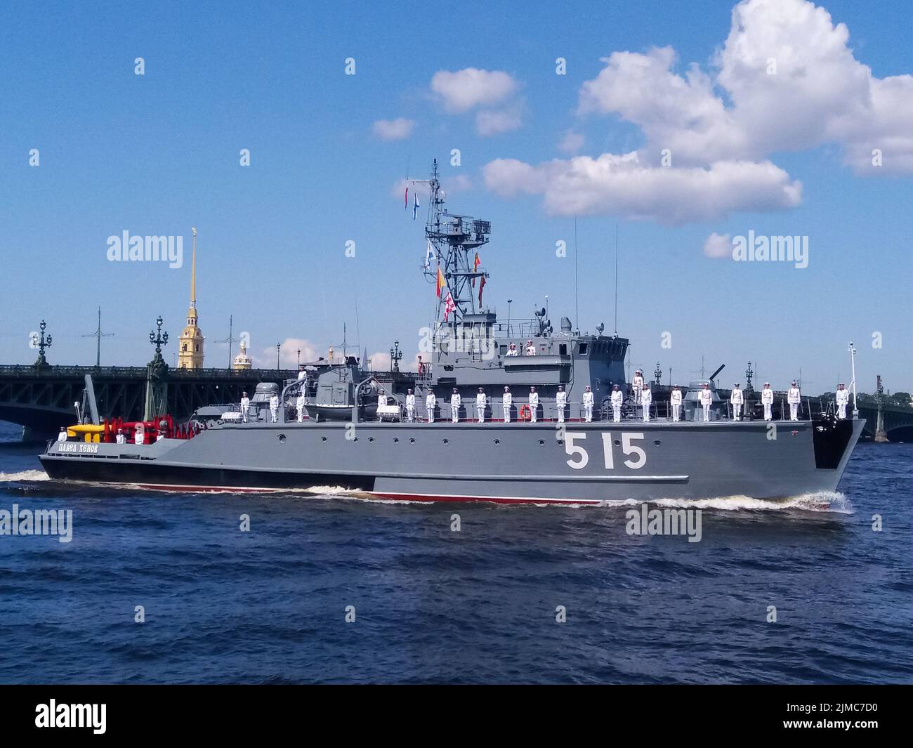 The parade of naval technology. Gray warship with sailors in formal white uniform on board against the background of the bridge Stock Photo