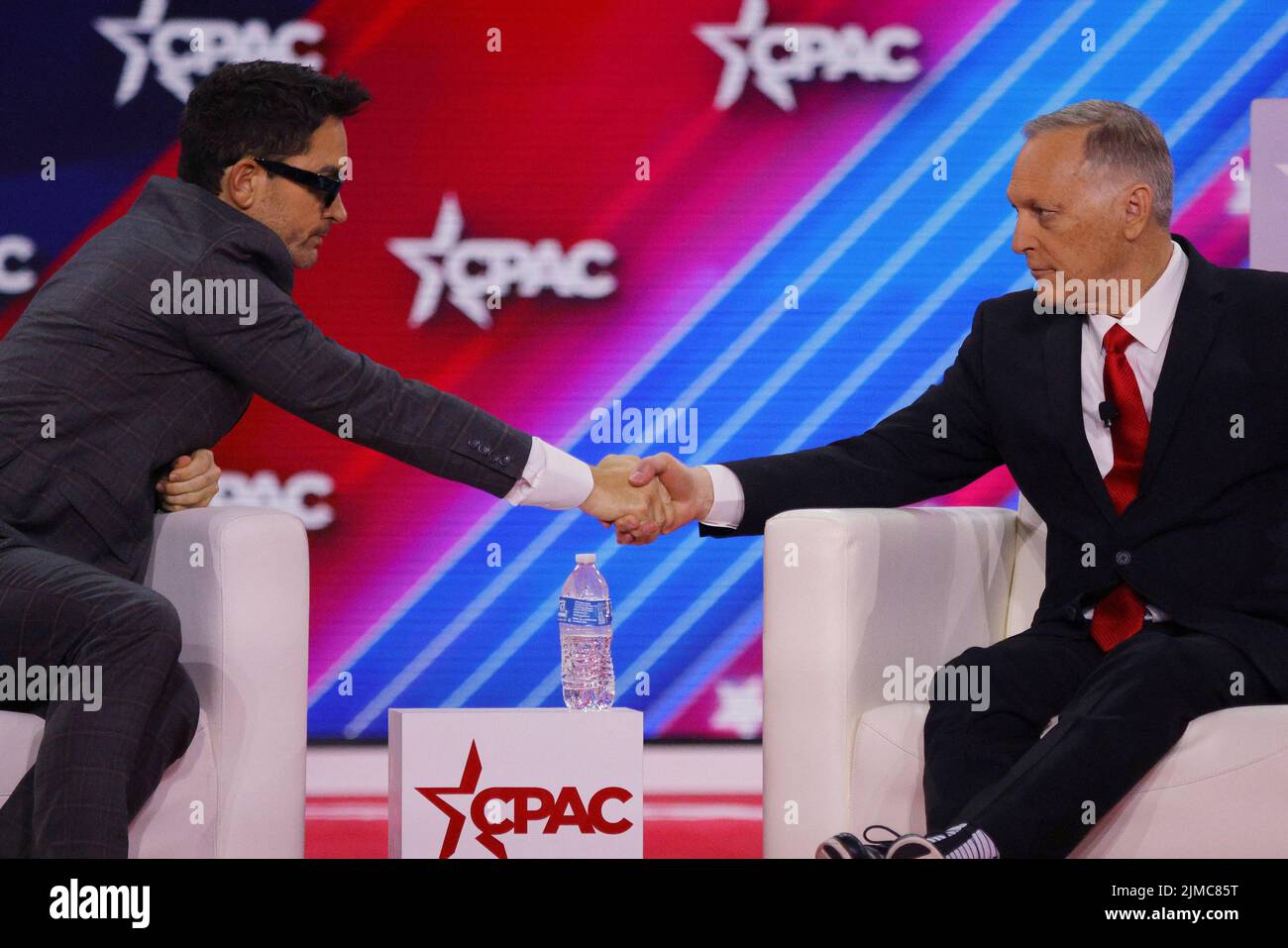 Brandon Straka, who was convicted on charges linked the January 6 attacks on the U.S. Capitol, shakes hands with U.S. Representative Andy Biggs (R-AZ) onstage at the Conservative Political Action Conference (CPAC) in Dallas, Texas, U.S., August 5, 2022.  REUTERS/Brian Snyder Stock Photo