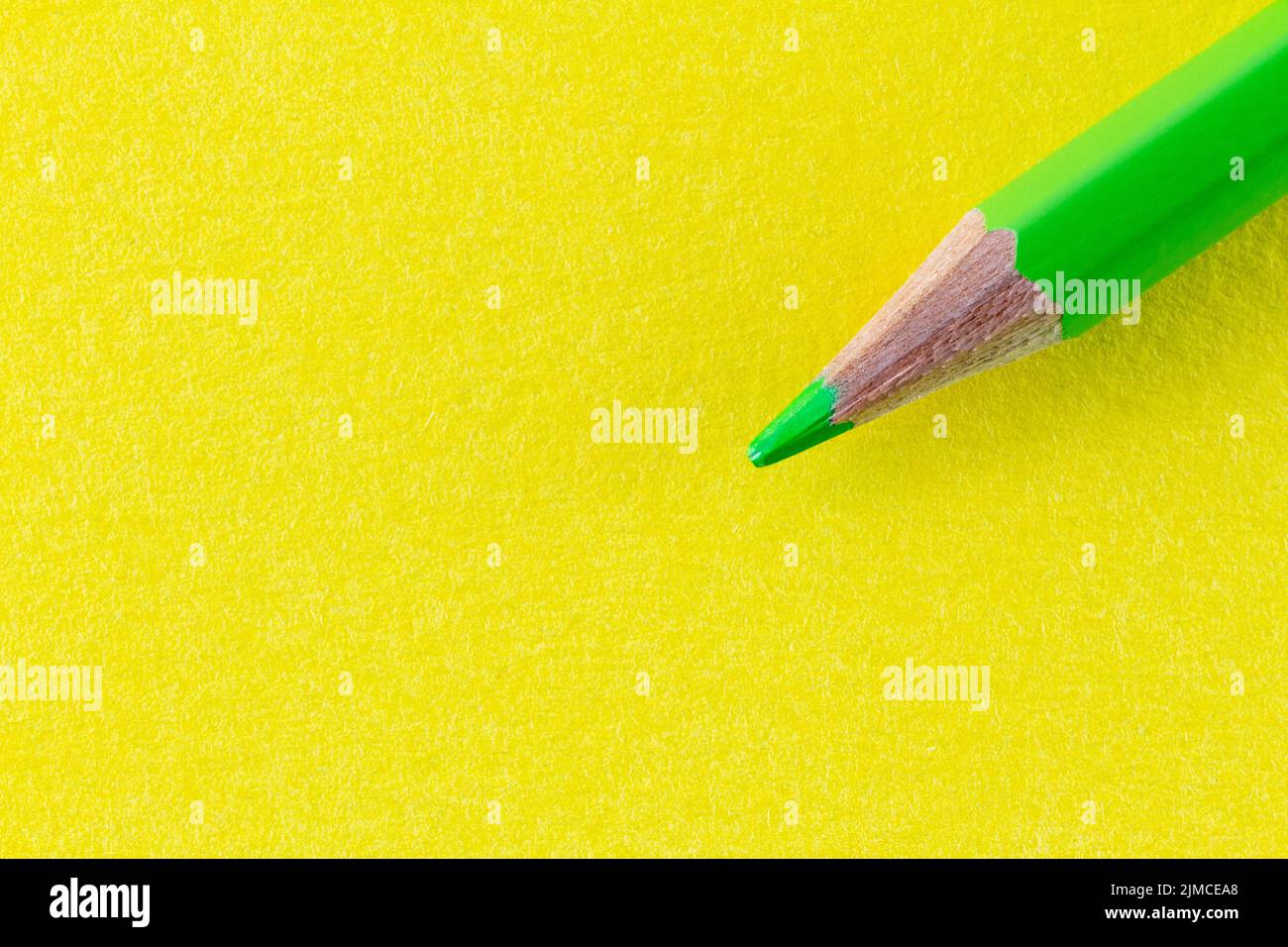 Green color pencil on yellow color paper arranged diagonally. Stock Photo