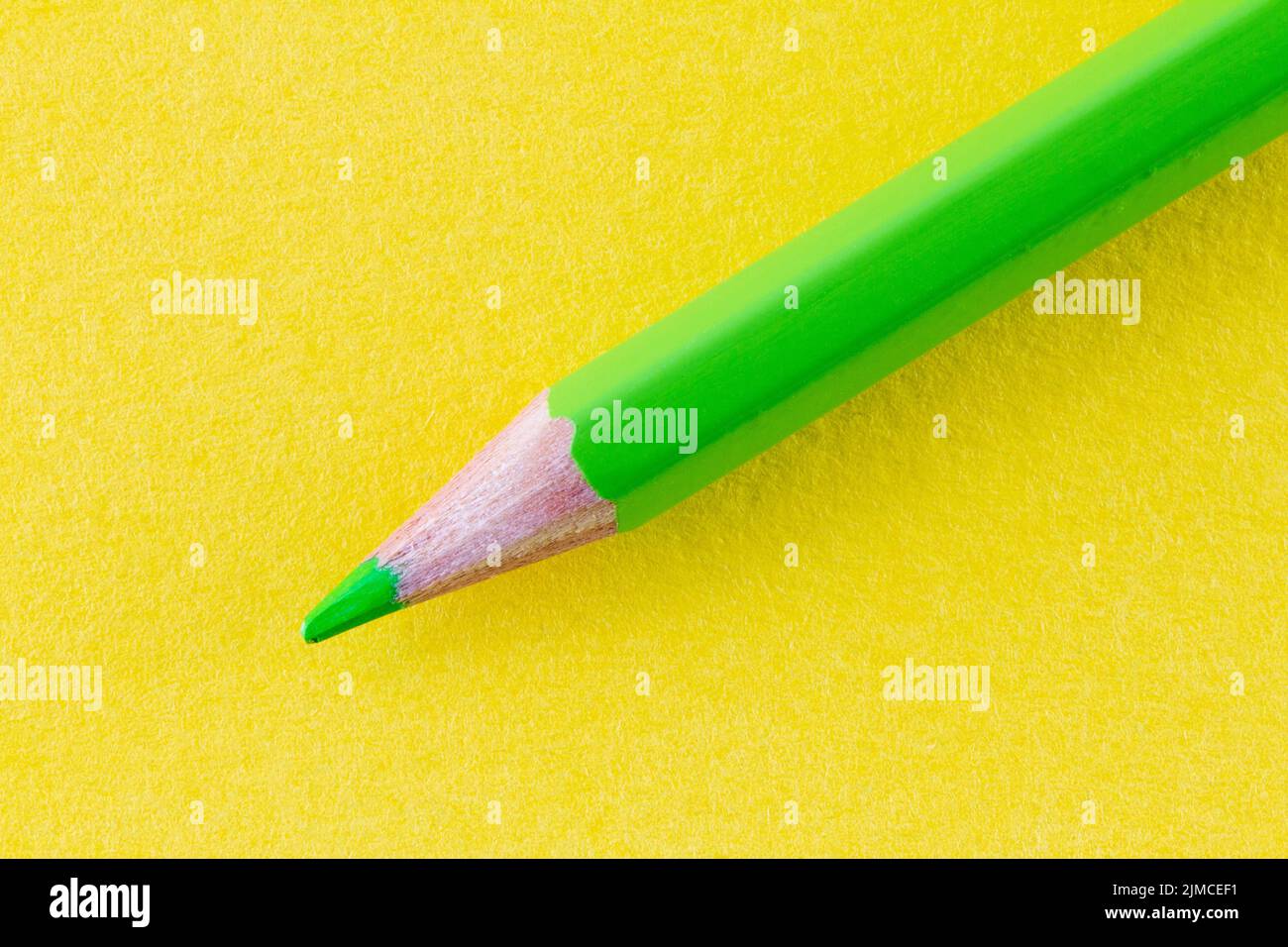 Green color pencil on yellow color paper arranged diagonally. Stock Photo