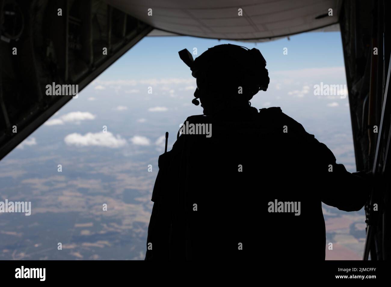 U.S. Marine Corps Capt. Justin Hoot, a team leader with 3rd Reconnaissance Battalion, 3rd Marine Division, III Marine Expeditionary Force, looks out the back of a C-130 Hercules at Hearne Municipal Airport, Hearne, Texas, July 20, 2022. This training was conducted during exercise Desert Eagle 2022 to reinforce proper techniques and the Marines’ proficiency in support of future III MEF operations within the Indo-Pacific region. (U.S. Marine Corps photo by Cpl. Zachary Sarvey) Stock Photo