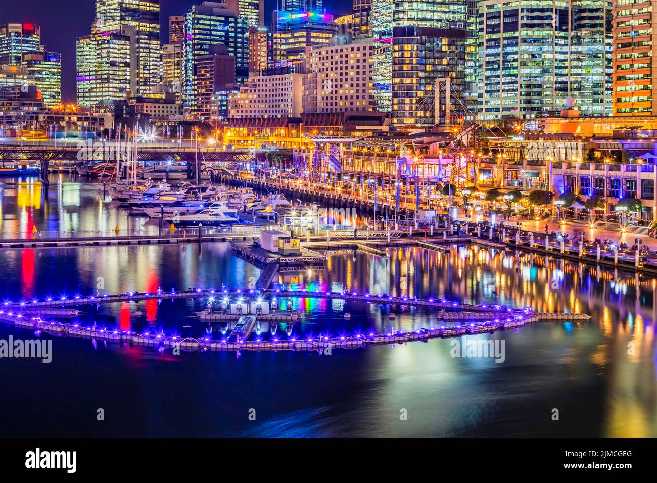Scenic brightly illuminated Darling Harbour waterfront in sydney city CBD at sunset with water fountain floaging on Coockle bay. Stock Photo