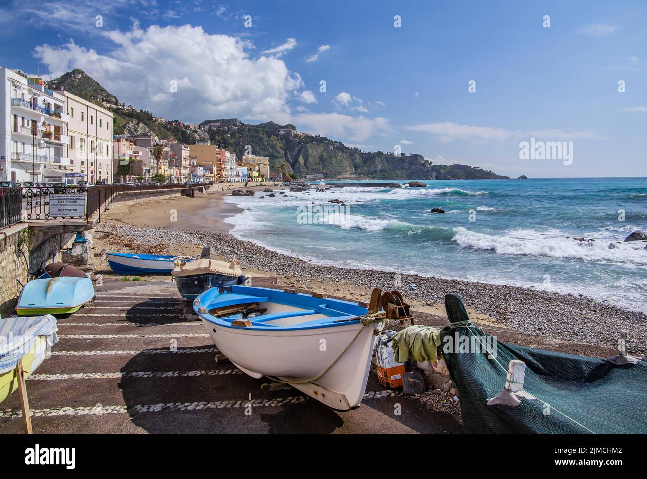 Fishing boats on the beach with sea surf in front of the promenade, Giardini-Naxos, east coast, Sicily, Italy Stock Photo