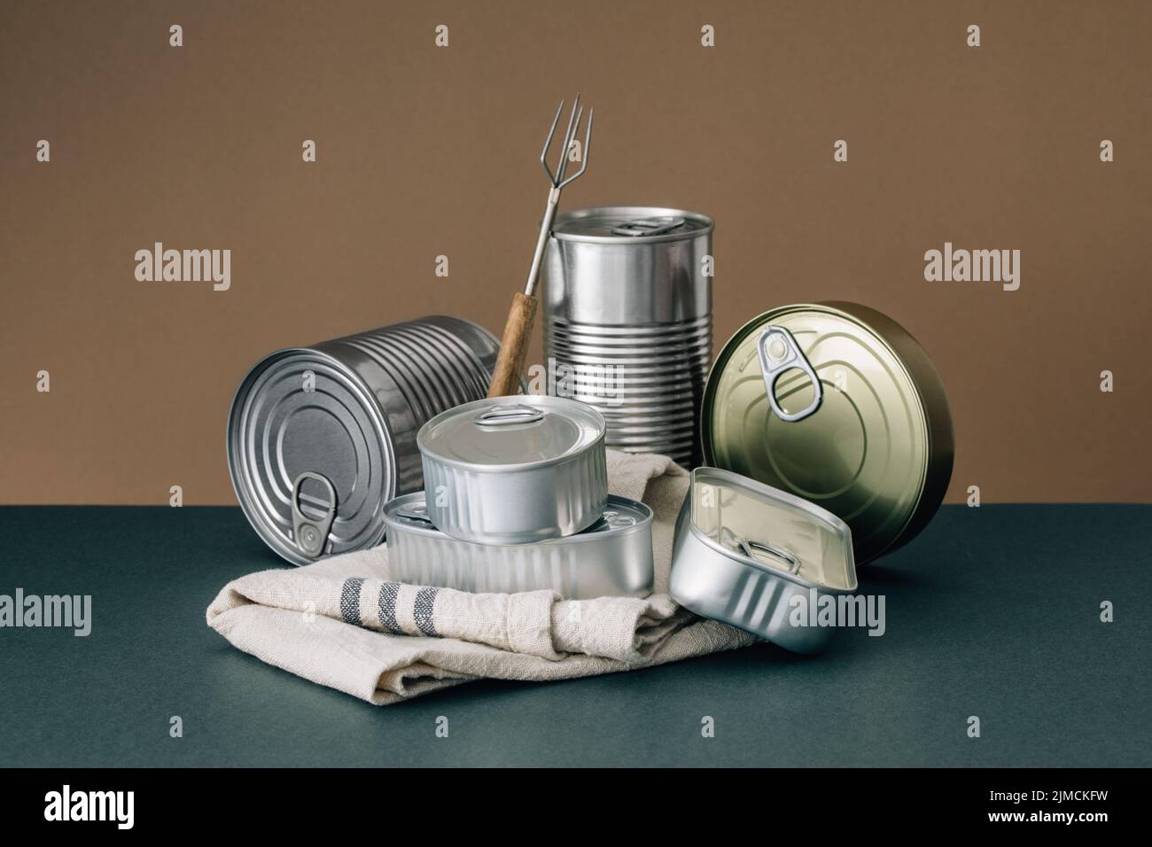 Stacked unopened cans on cloth on a brown and green background Stock Photo