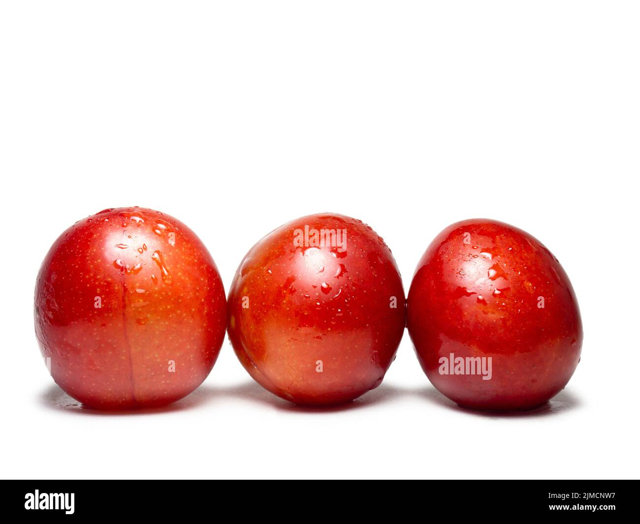 Red cherry plum in water droplets. Ripe fruit on a white background