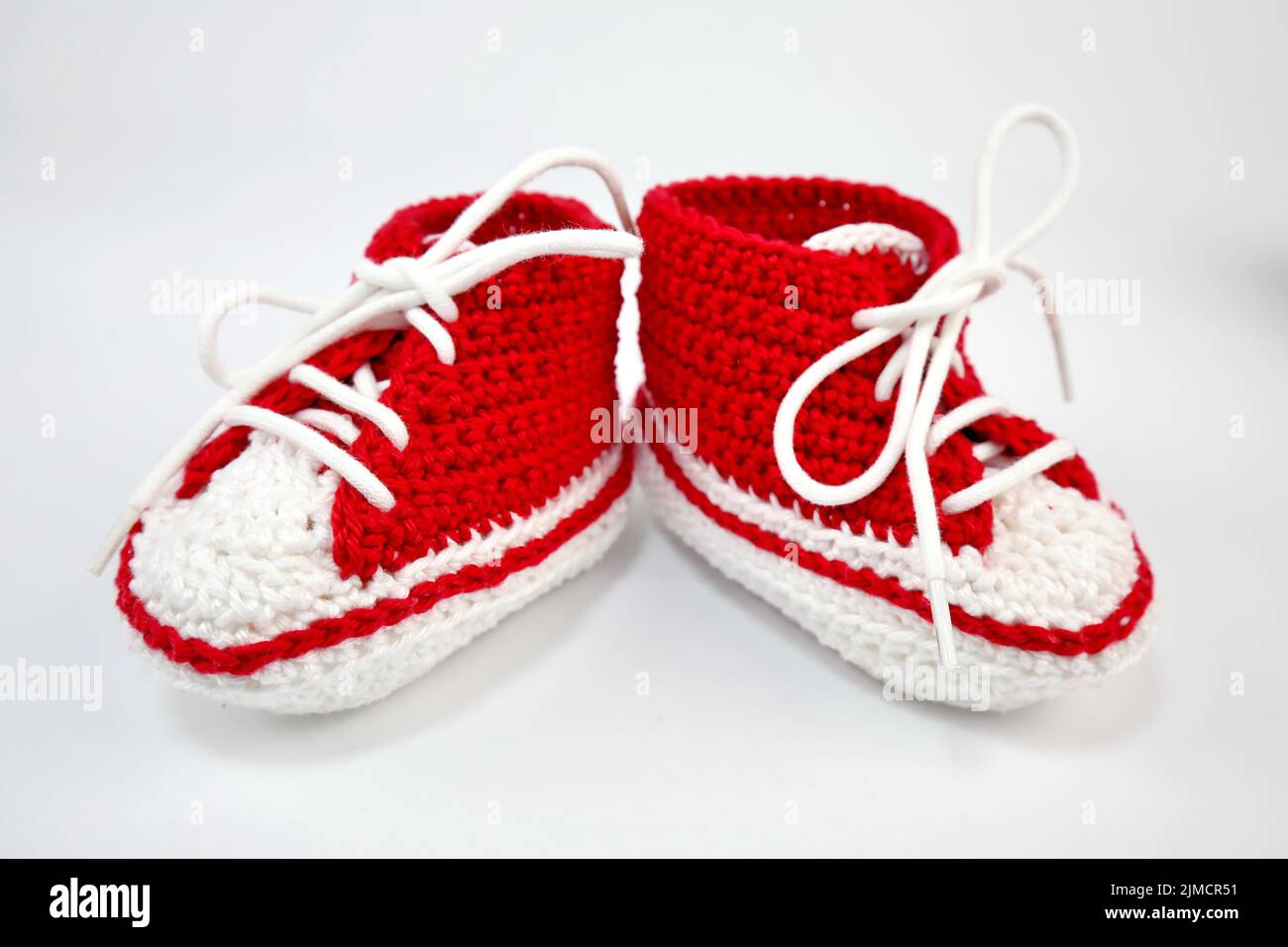 Baby shoes or crochet shoes in red and white isolated against a white ...