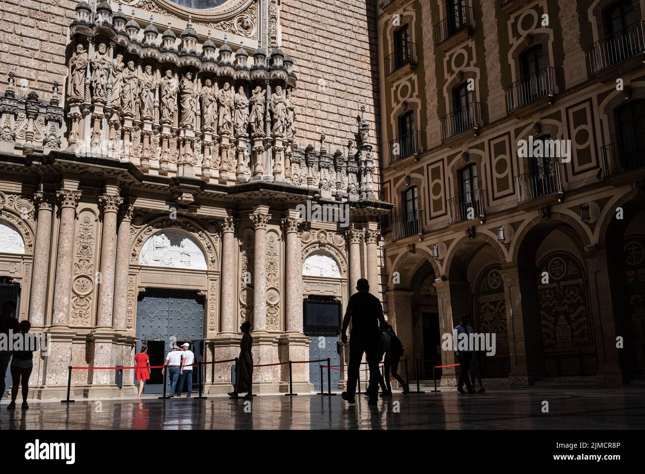 Facade and courtyard at the entrance of the Basilica of the Benedictine Abbey of Montserrat, Barcelona Province, Spain. Tourists and pilgrims visiting Stock Photo