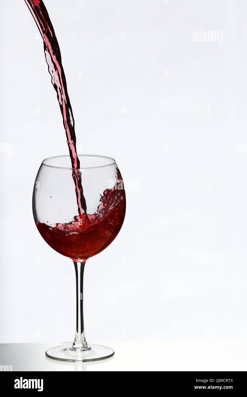Pouring a glass of red wine. Released against a white background Stock Photo