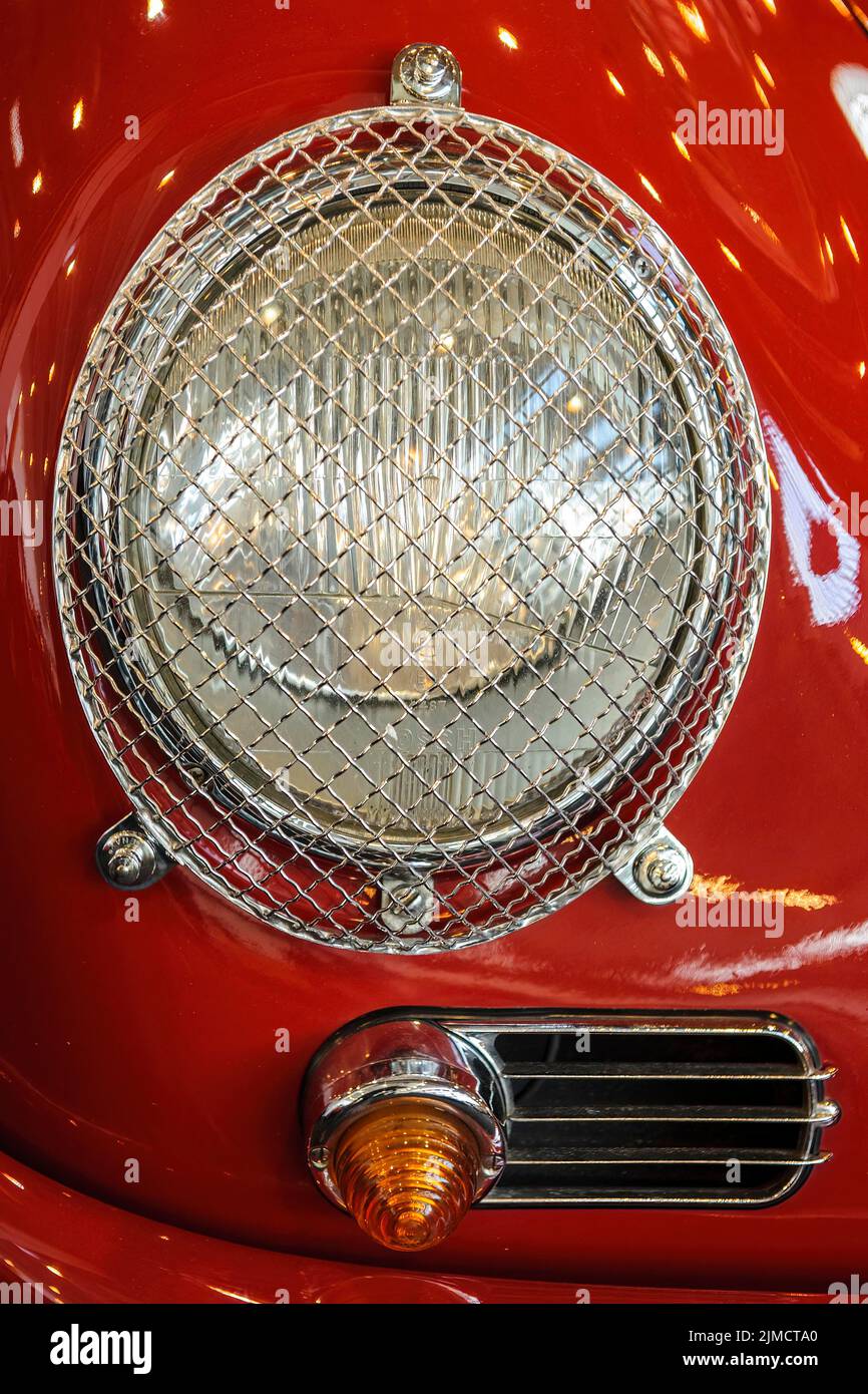 Round headlamp with grille as protection against stone chipping Glass
