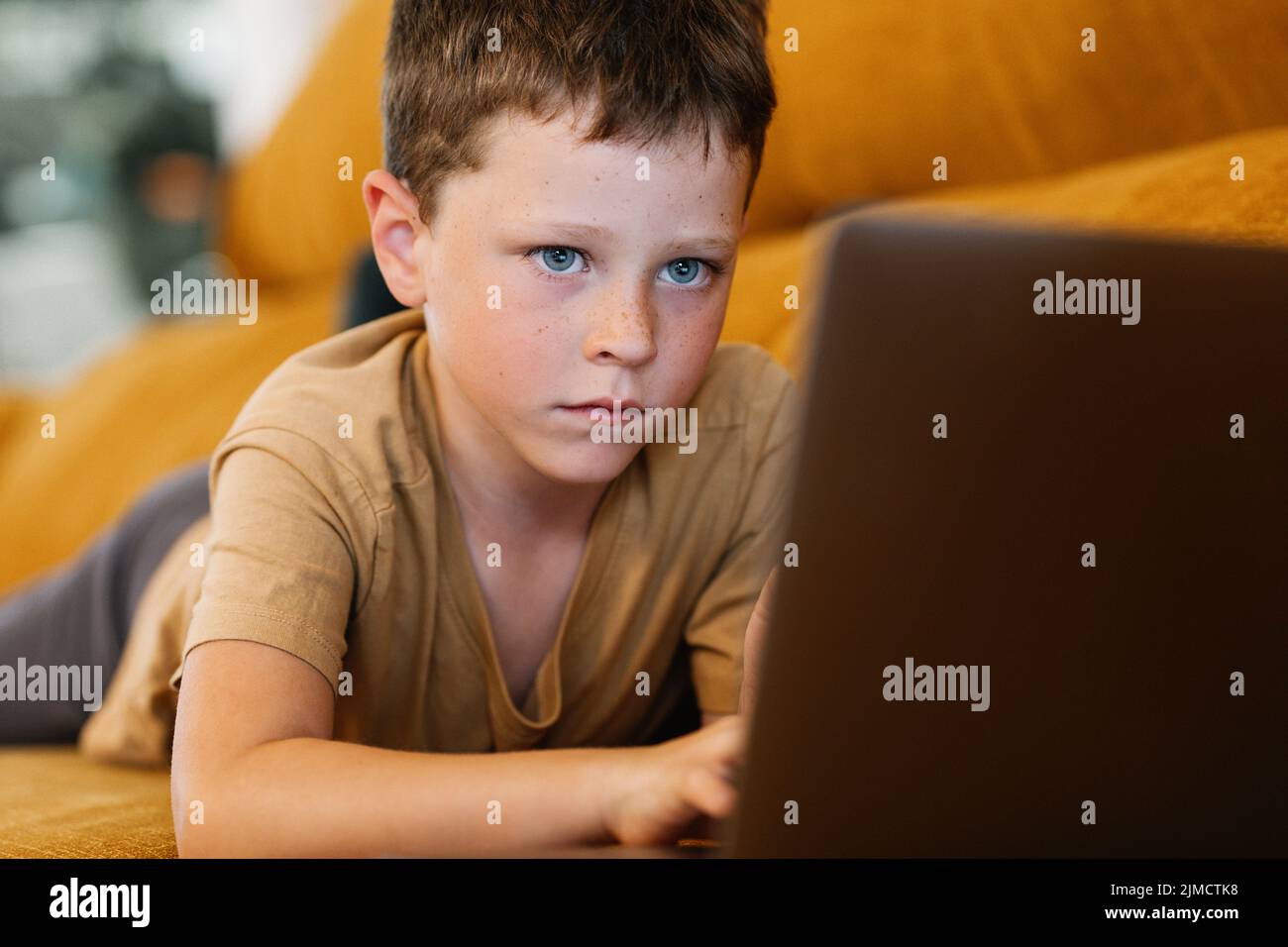 Boy lying on a sofa using the laptop while at home Stock Photo - Alamy