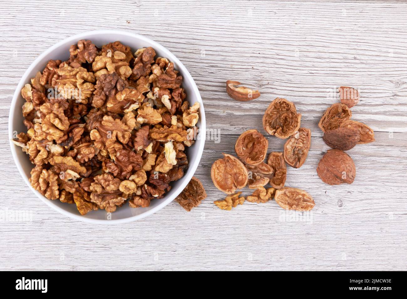 Walnuts in white bowl on wooden surface Stock Photo