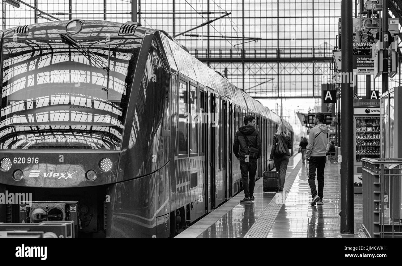 Black and white, travellers and trains at Frankfurt main station, Hesse, Germany Stock Photo