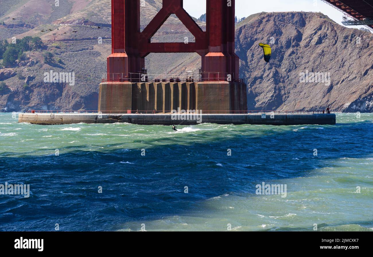 Windsurfer lifted into the air against the backdrop of a NYK Line ship above white caps beneath the Golden Gate Bridge.  Editorial Use Only Stock Photo