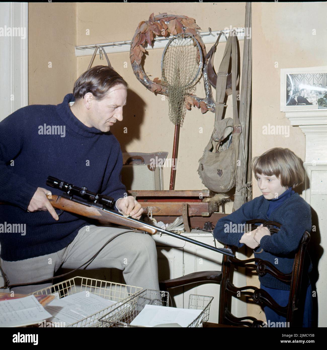 Circa 1965, London, England, United Kingdom: British Racing driver INNES IRELAND with his 8-yr old daughter, CHRISTINNE at home with his hunting rifle and gear. Lieutenant Robert McGregor Innes Ireland (12 June 1930 C 22 October 1993), was a British military officer, engineer, and motor racing driver, with 1 Formula 1 victory, and 8 Tourist Trophies. (Credit Image: © Keystone USA/ZUMA Press Wire) Stock Photo