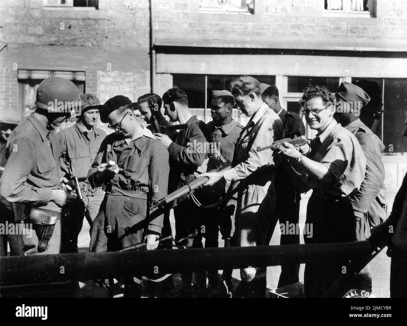 US and French soldiers comparing their respective weapons in Couterne, Orne in 1944. Stock Photo