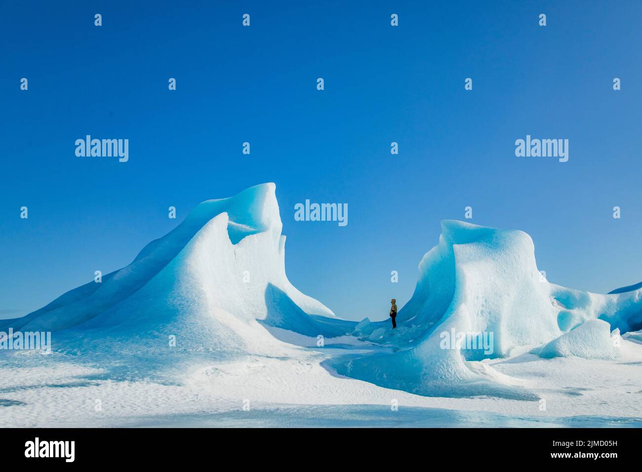 Unrecognizable traveler hiker admiring spectacular scenery of frozen seashore with ice and snow in winter in Iceland Stock Photo