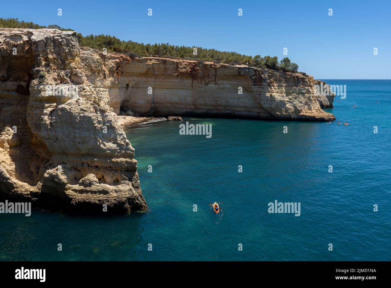 From above spectacular view of anonymous people on a boat and kayak under blue sky in Algarve Portugal Stock Photo