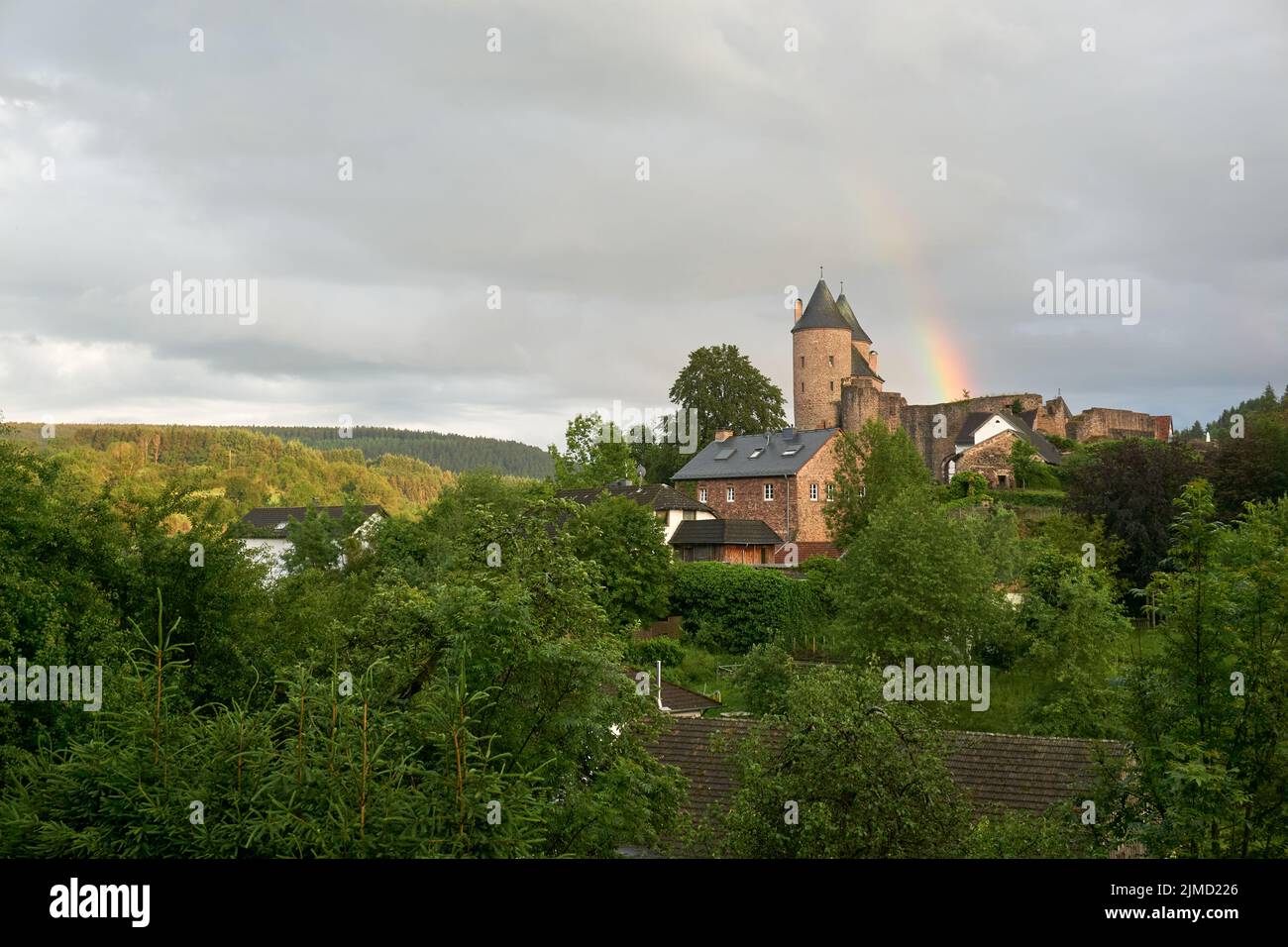 Landscape photo of Muerlenbach in the Eifel in summer with a rainbow and Bertrada Castle. Stock Photo