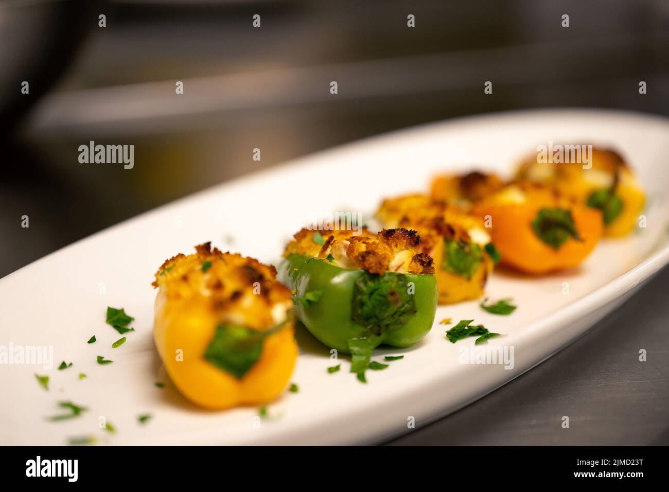Macro image of stuffed mini peppers lined up on an oval plate with parsley for garnish Stock Photo