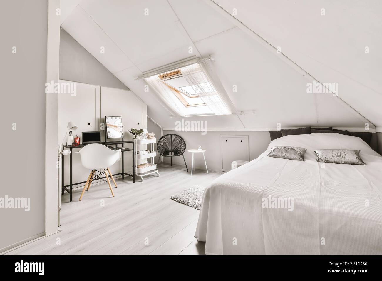 Comfortable bed with white walls next to a studio table under a bright window Stock Photo Alamy