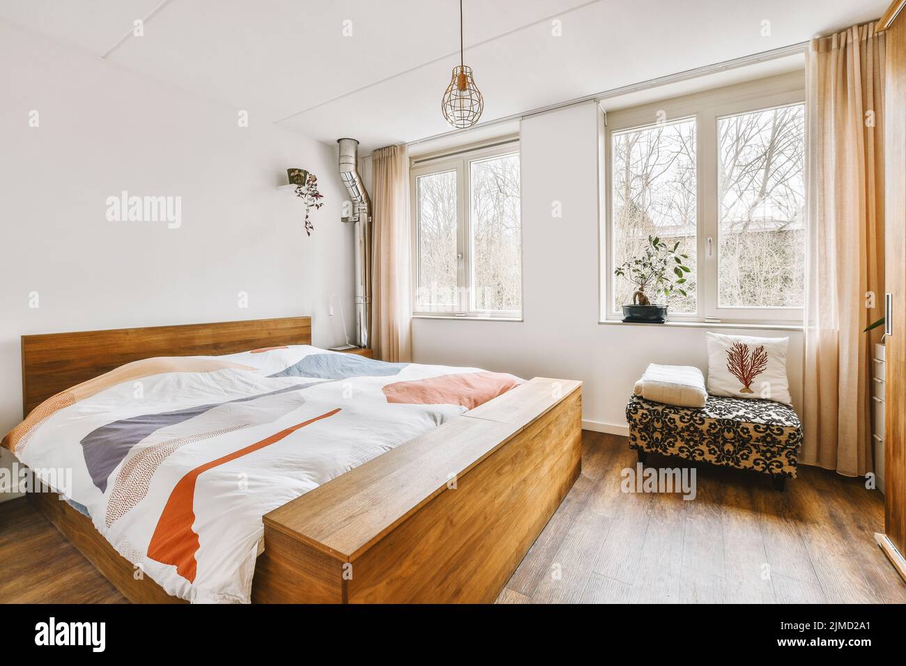 Comfortable bed next to a bright window and wooden floor Stock Photo