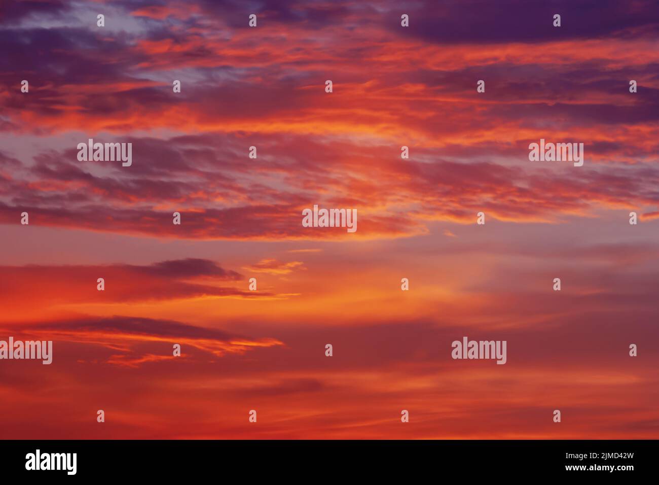 Red orange purple colorful clouds in darkening sky at sunset Stock Photo