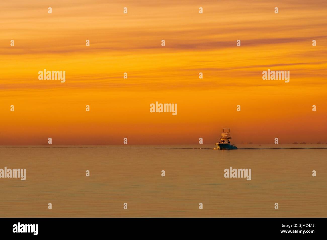 A fishing boat crosses Mobile Bay near Fairhope, Alabama, at sunset in a composite image. Stock Photo