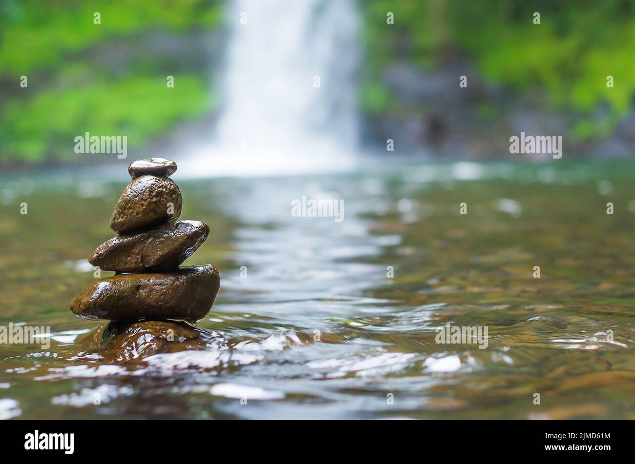 Great concept of spiruality, tranquility and meditation, land art with stones in waterfall. Stock Photo