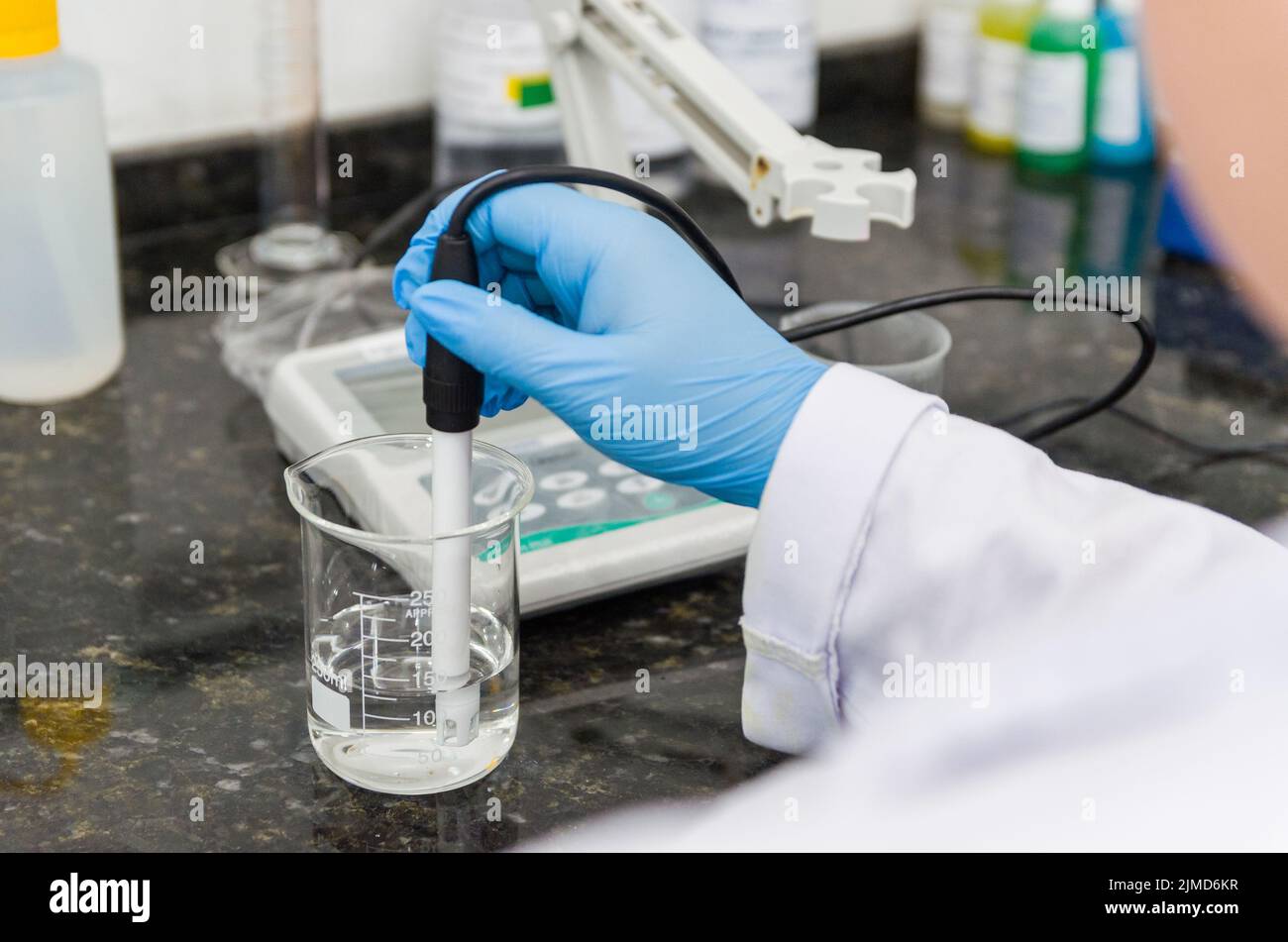 Woman hands performing pH test on pH meter electronic instrument for quality control in chemical ind Stock Photo
