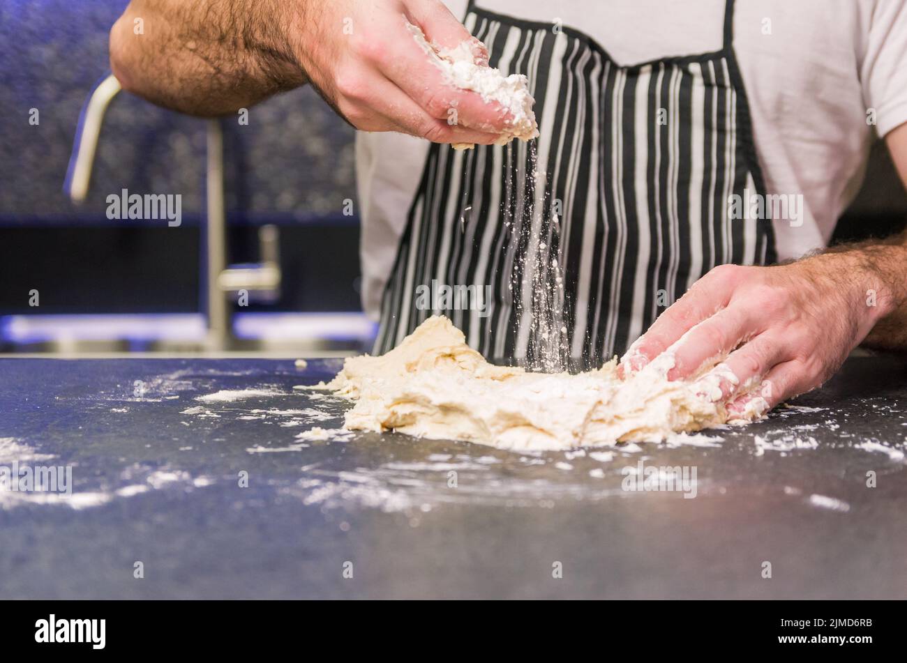 Man preparing pizza dough on black granite table Stock Photo
